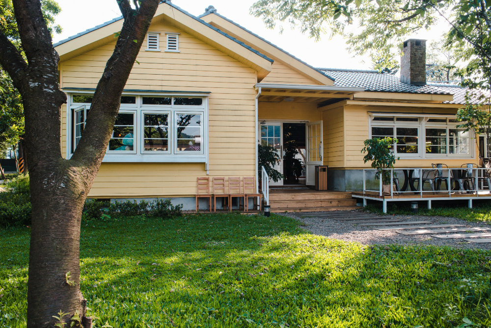 charming yellow house with wooden windows and green grassy garden