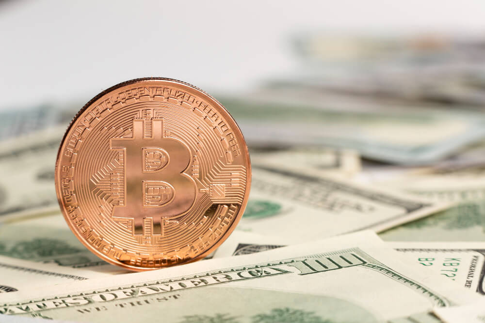 copper bitcoin on top of dollar bills 1