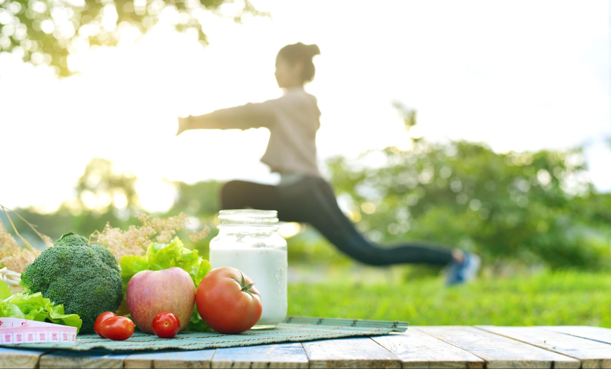 frutas a frente comida saudavel e mulher ao fundo verde